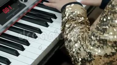 穿着闪亮的金色衬衫的少女弹电钢琴。 孩子们`手指按合成器的键